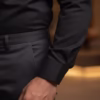 A close-up shot of a man's arm showcasing a premium black Giza cotton dress shirt with a tailored one-button round cuff, neatly tucked into dark gray formal trousers.